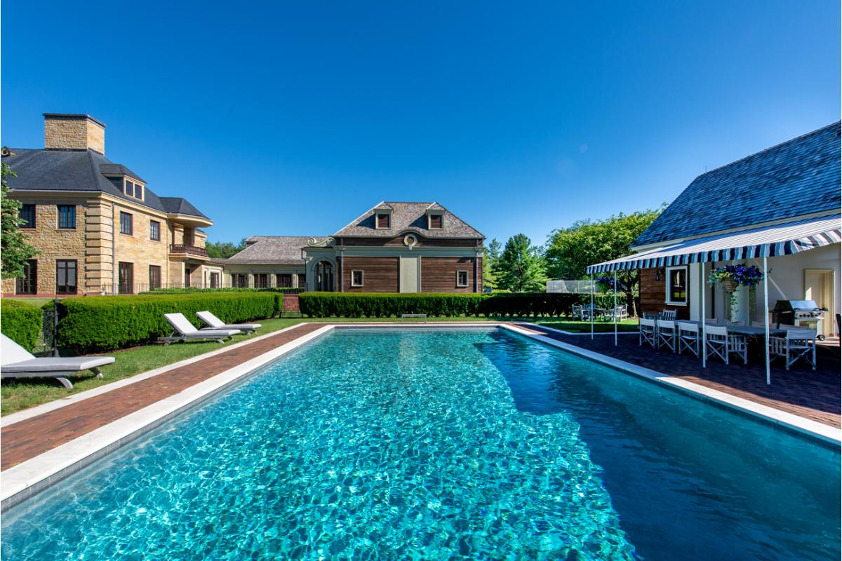 A swimming pool in the backyard surrounded by green plants.