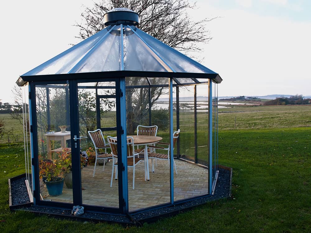 A sunroom located outside the actual house. This blue-colored room has a fresh garden finish.