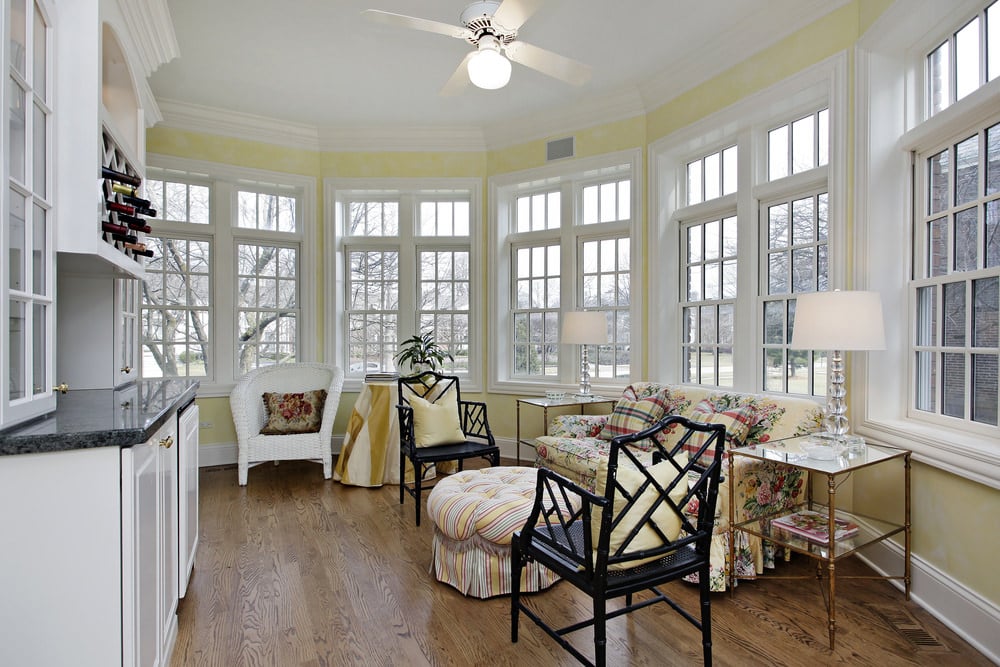 Country-style sunroom with hardwood floor and a floral couch.
